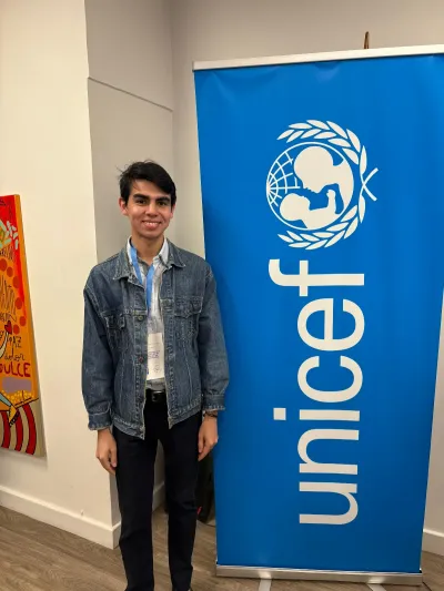 A young man standing next to a UNICEF banner smiling
