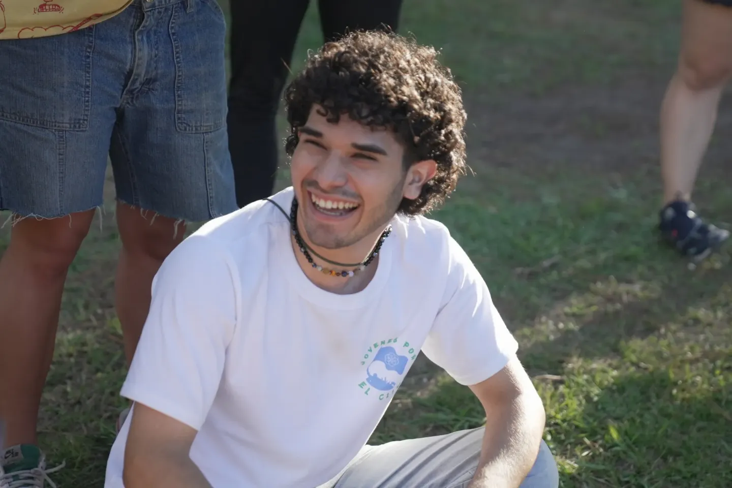 A photo of a young man sitting on the ground, smiling and laughing