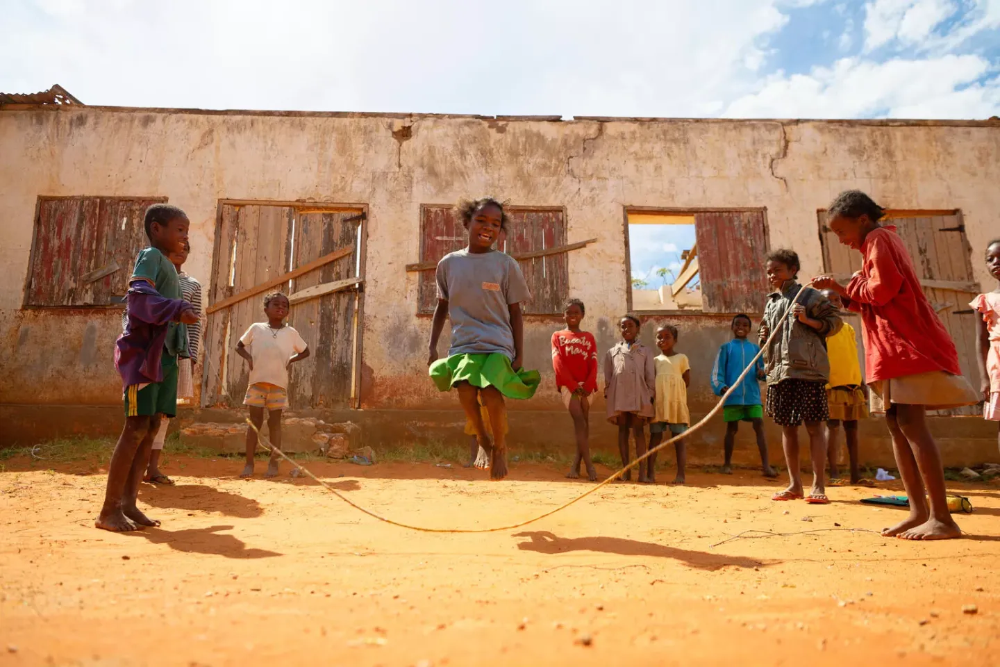 Madagascar: schoolkids playing bungee jumping in the schoolyard in a good mood.
