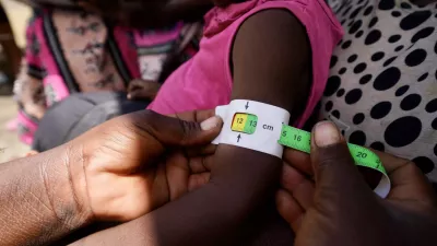 A child is being measured with a MUAC tape.