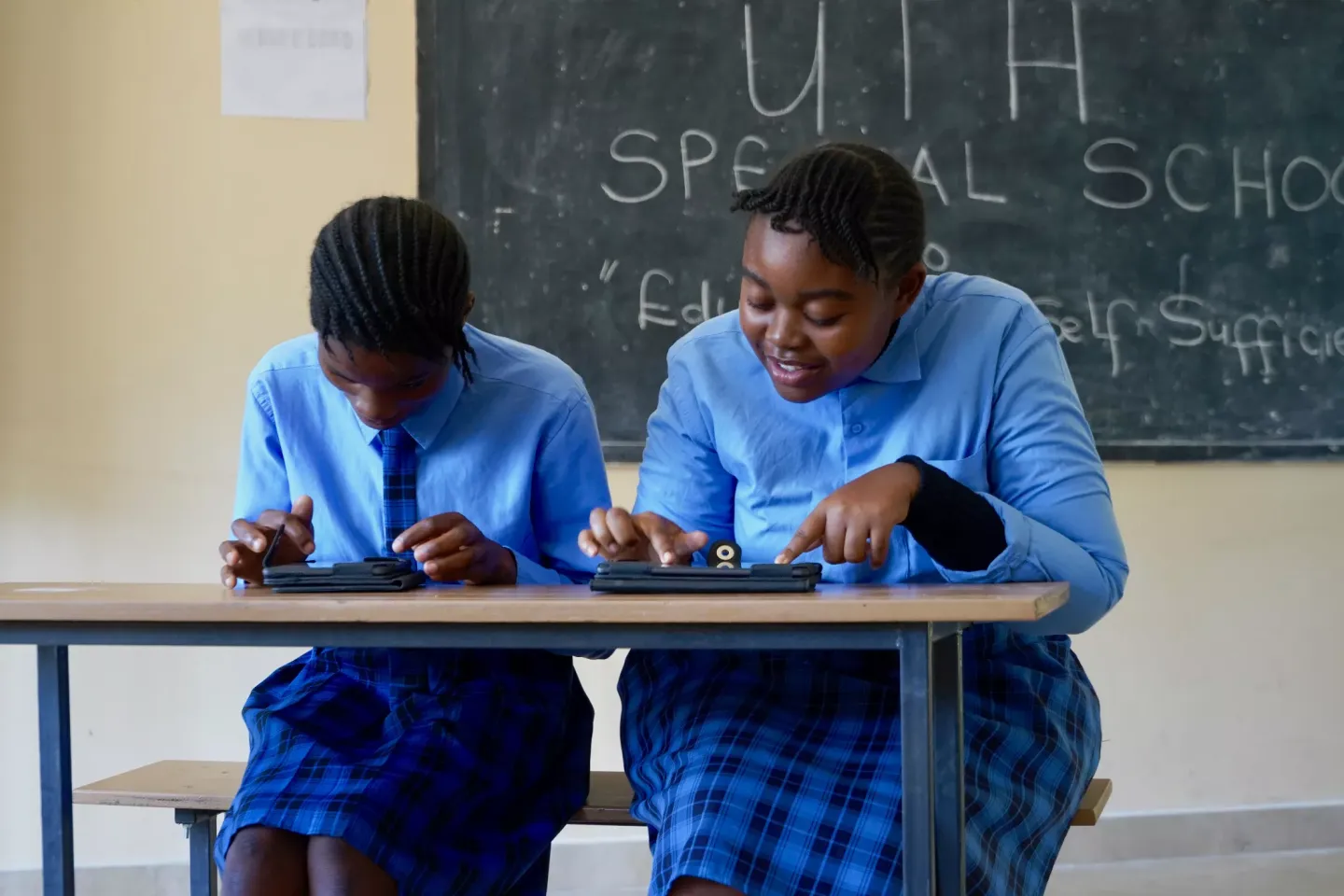 Two young girl pupils make use of their assistive devices