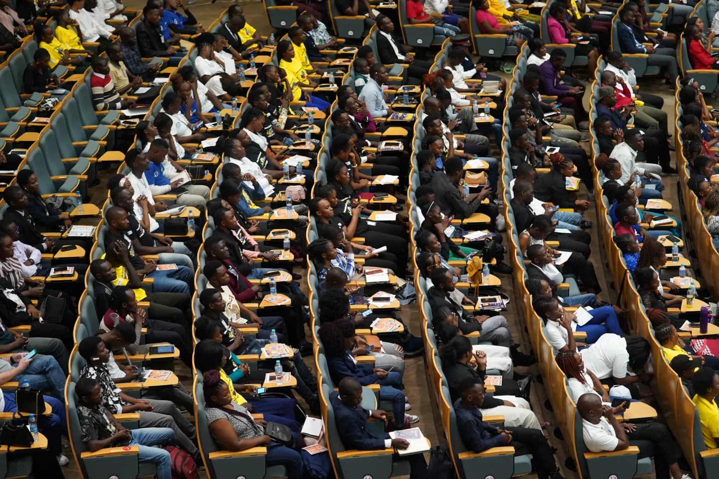 A picture of youths seated in a big conference room.