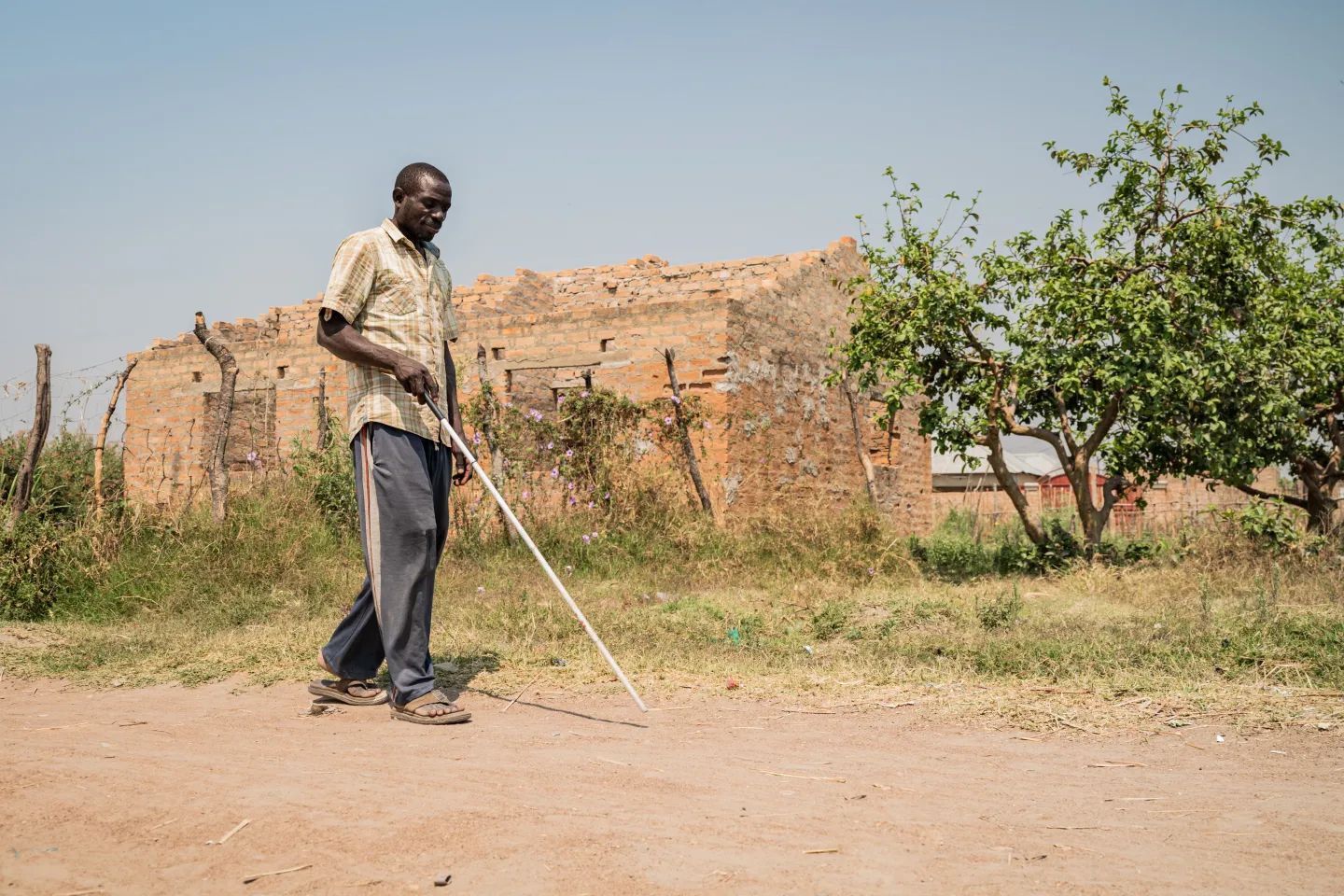 Elais, a man with a visual impairment,  walking in his community 