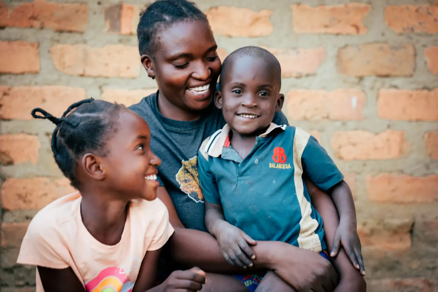 Caren Mutinta poses with her two children outside their house in Monze district.