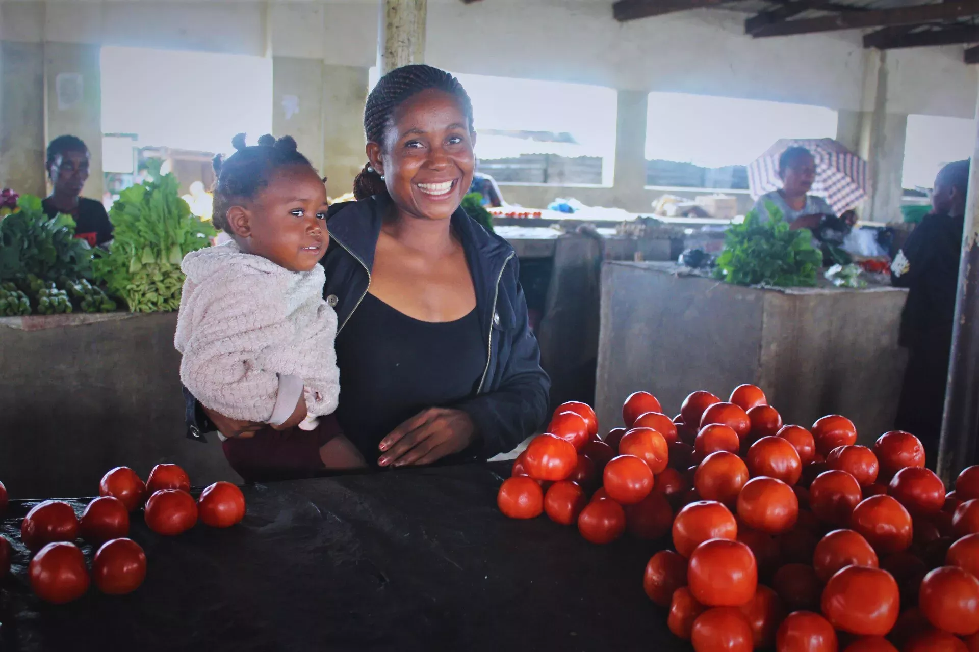 A mother carrying her baby and smiling at her baby at a market