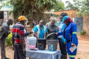 A group of men and women checking buckets for washing hands
