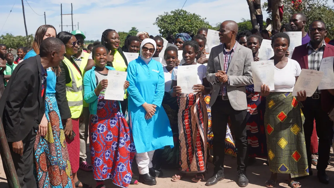 Dr. Saja Farooq Abdullah joins adolescent mothers displaying birth certificates during a community engagement in Chifunabuli District, Luapula Province.