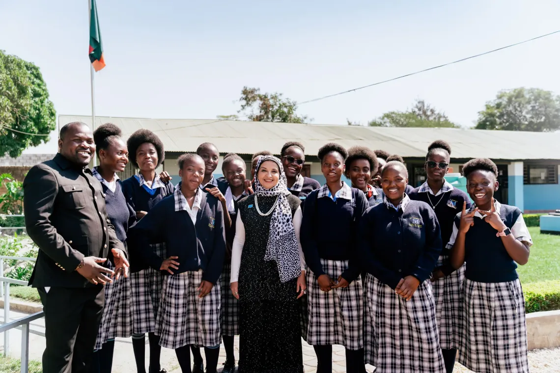Dr. Saja Farooq Abdullah, UNICEF Zambia Representative, and ICT teacher Collins Chipasa pose with learners at St. Monica's Girls' Secondary School