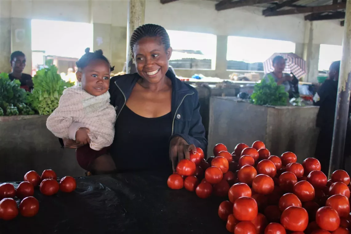 A mother carrying her baby and smiling at her baby at a market