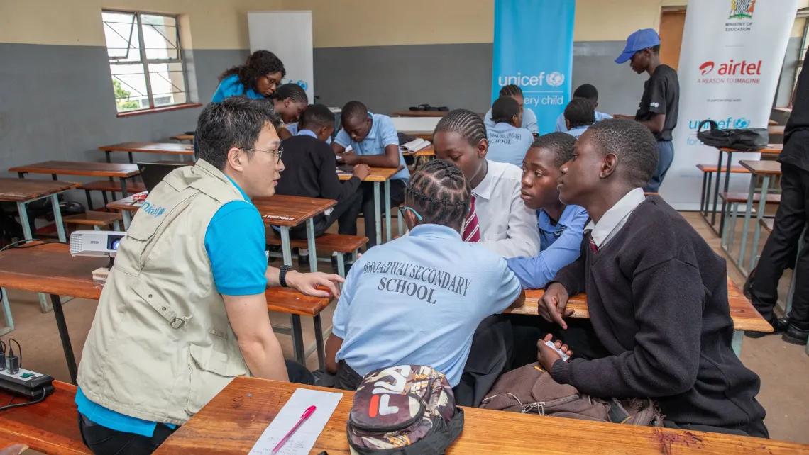 A UNICEF staff member engages in a group discussion with secondary school students from Broadway Secondary School during a digital literacy session