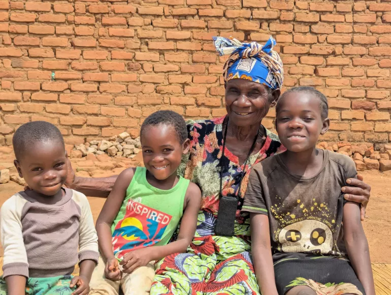 Fridah with her three school-age grandchildren, who benefit from the Social Cash Transfer programme