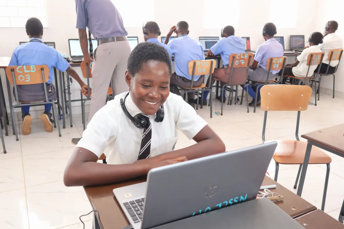 Female student smiling as she uses her laptop in class