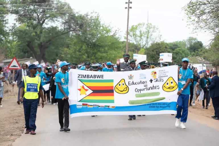 Adolescent boys hold up Zimbabwe banner while leading in the World Childen's Day march